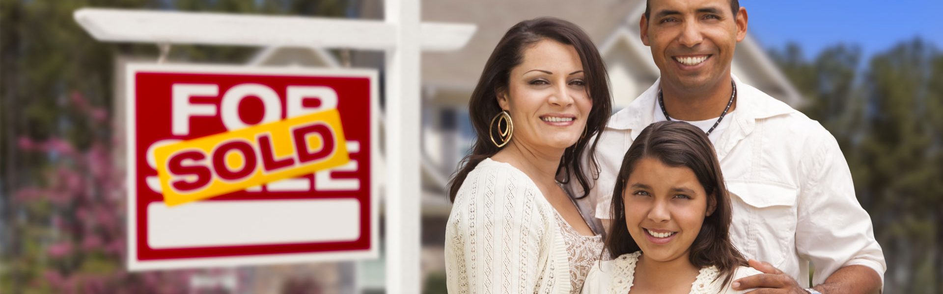 a man and woman standing in front of a for sale sign.